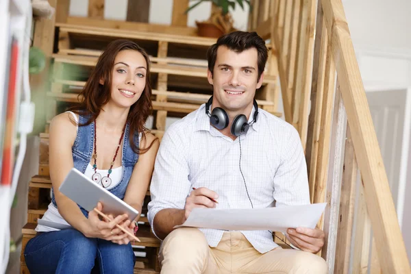 Portrait of two young people sitting at the stairs in office