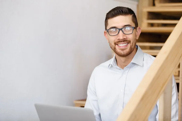 Portrait of young man sitting at the stairs in office