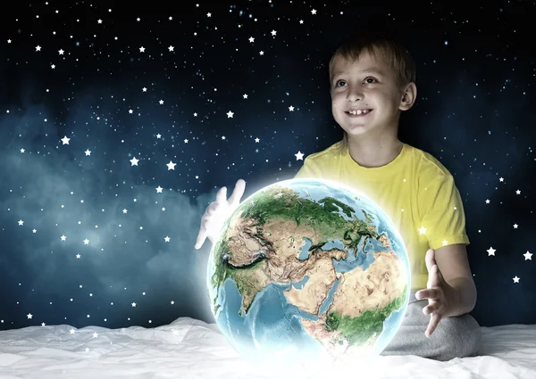 Boy sitting in bed and holding Earth planet