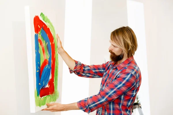 Young male artist standing with a picture