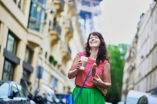 French woman walking with coffee to go and baguette