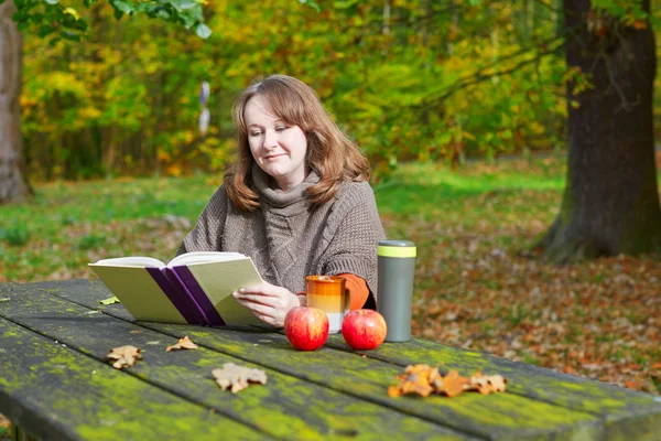 Girl having a picnic in park on a fall day