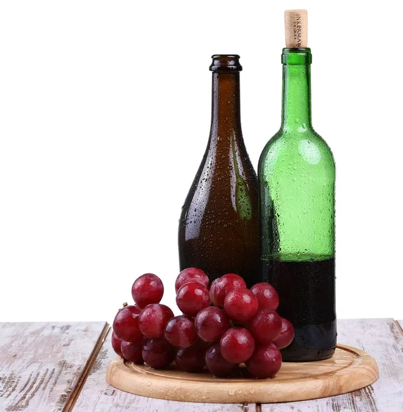 Wine glass with red wine, bottle of wine and grapes isolated over white background