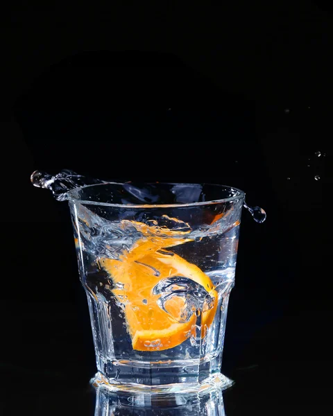 Slice of lemon splashing into a glass of water with a spray of w