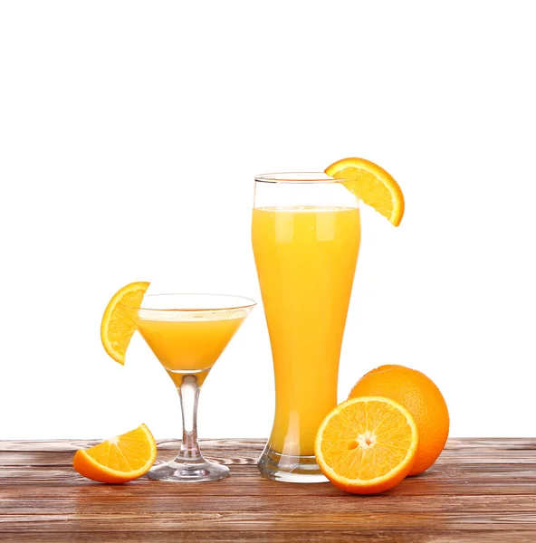 Glass of freshly pressed orange juice with sliced orange half on wooden table