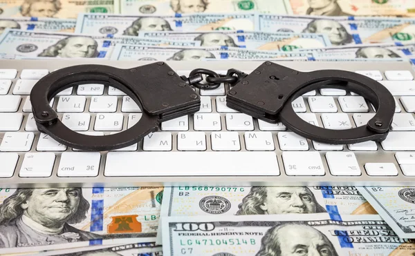 Steel handcuffs lying on a computer keyboard on the background o