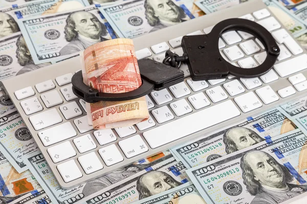 Steel handcuffs and roll of russian rubles lying on a computer keyboard