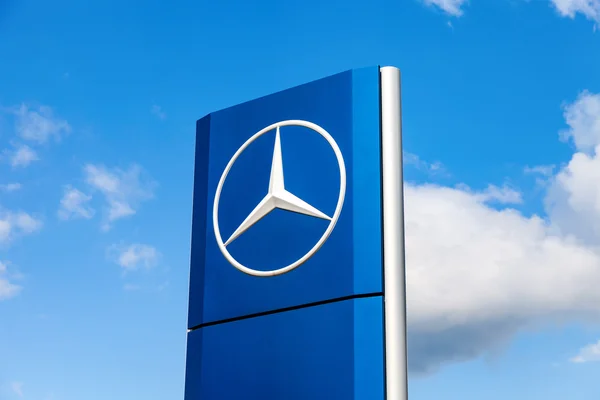 Official dealership sign of Mercedes-Benz over blue sky