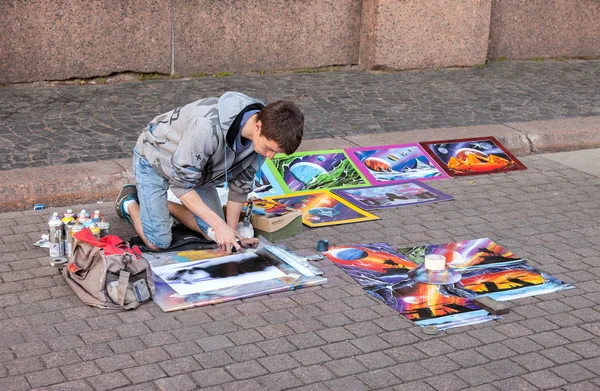 The young artist paints a pictures on a city street