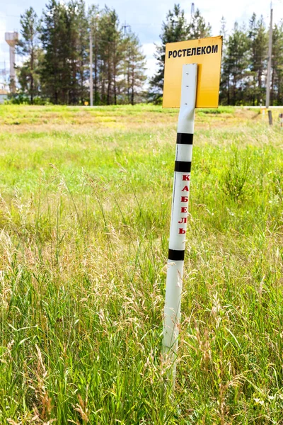 Warning sign in a field where communication cable Rostelekom. Te