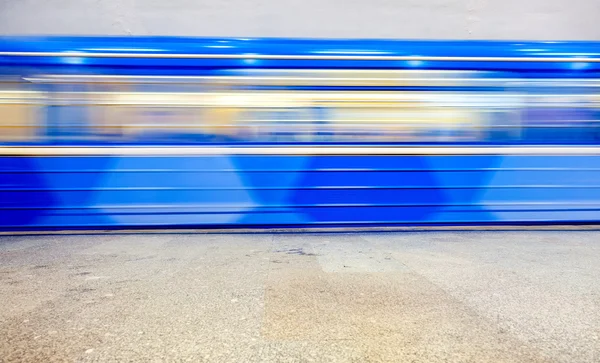 Blue subway train in motion at the underground station