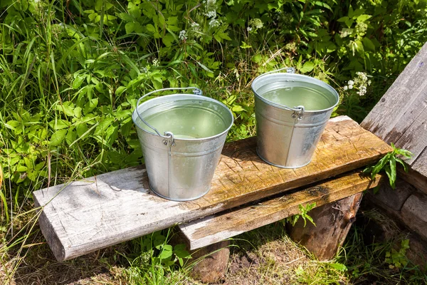 Buckets of water standing on a bench at the village water well