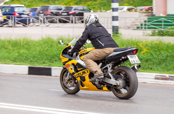 Biker in helmet on a motorcycle Suzuki racing on the road in cit