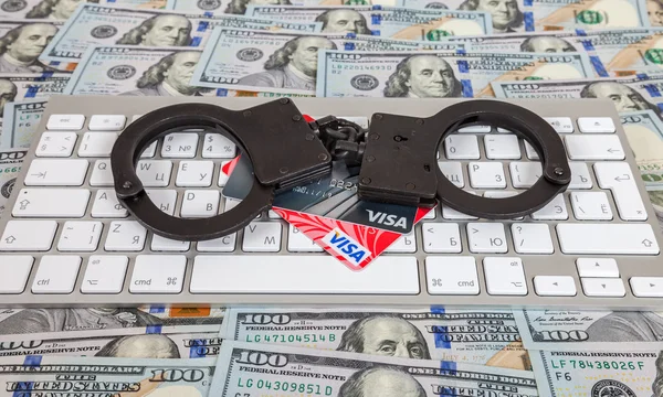 Steel handcuffs and credit cards lying on a computer keyboard