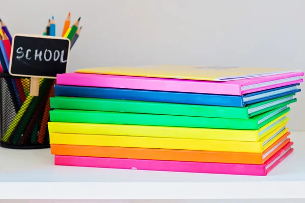 Multi colored books in stack on the light-coloured bookshelf