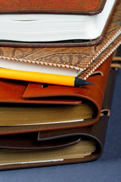 Pile of notebooks in leather covers and a pencil close up