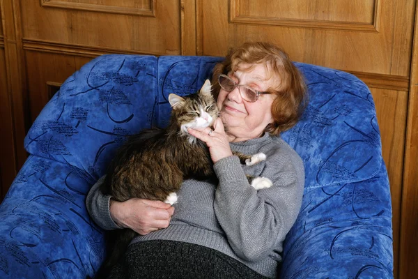 Old woman in an armchair with a cat on hands