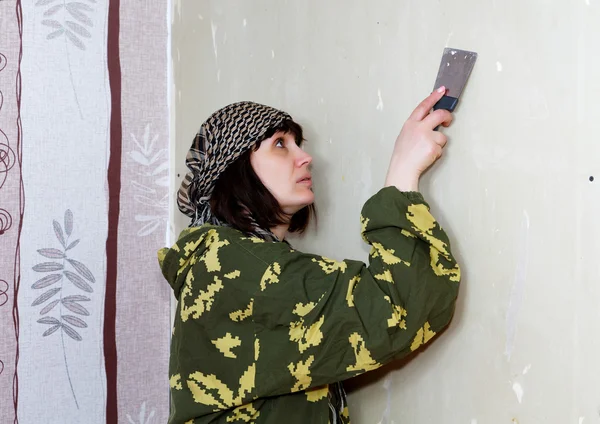 Woman scraped the old wallpaper off the wall