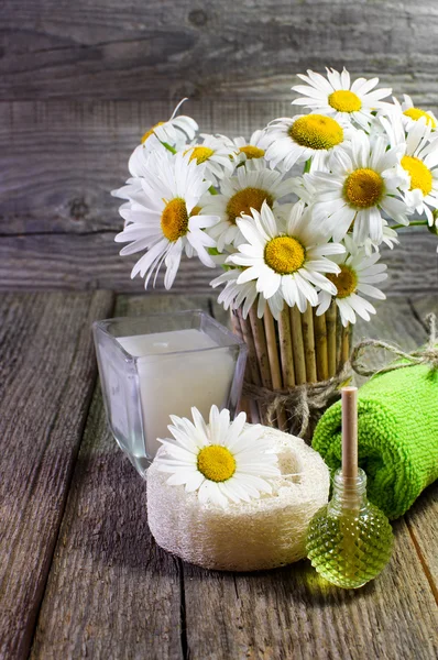 Spa still life. Beautiful daisies, candle and other accessories on wooden surface.