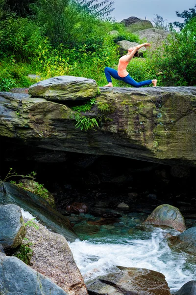 Sporty fit woman practices yoga Anjaneyasana in mountains