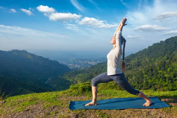 Woman doing yoga asana Virabhadrasana 1 - Warrior pose outdoors