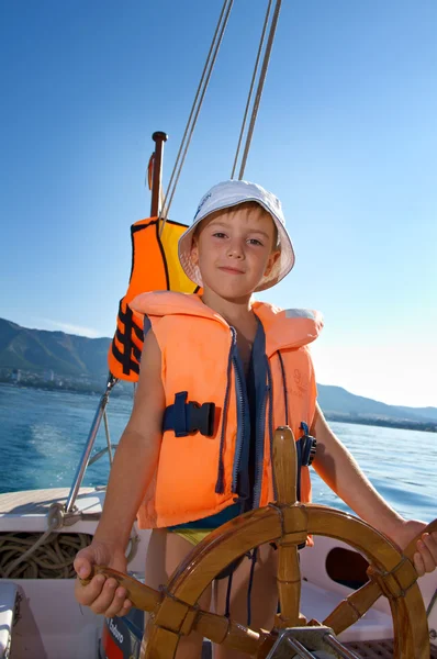 Little boy at sail boat wheel