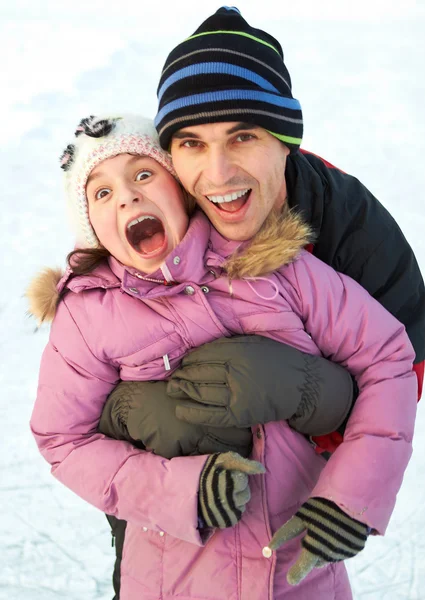 Dad hug his daughter and have fun in winter park