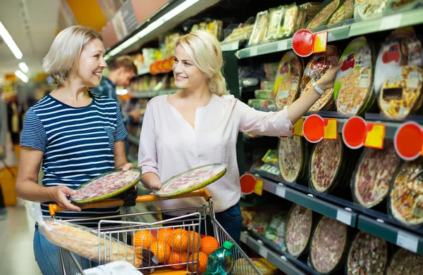 Adult girl helping mother in pizza section