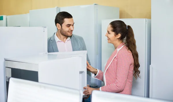 Young beautiful couple looking at large fridges