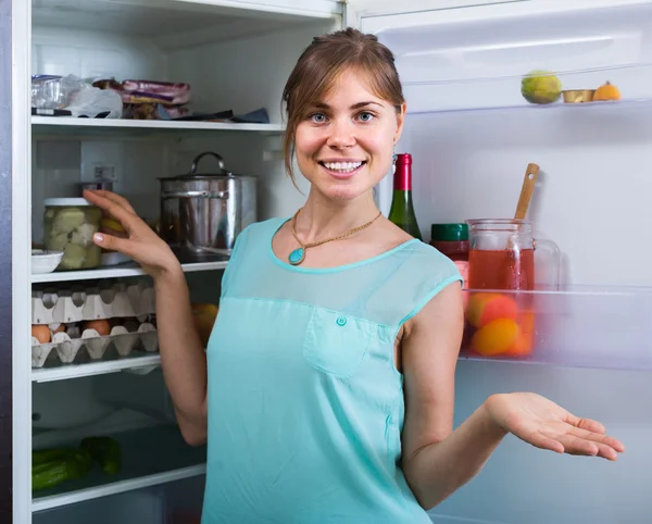 Girl arranging space of fridge shelves