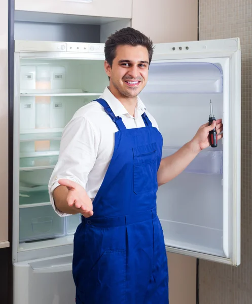 Handyman repairing refrigerator in kitchen