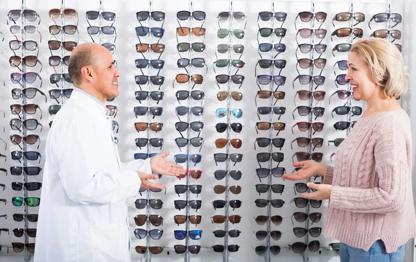 Woman choosing glasses in optics store