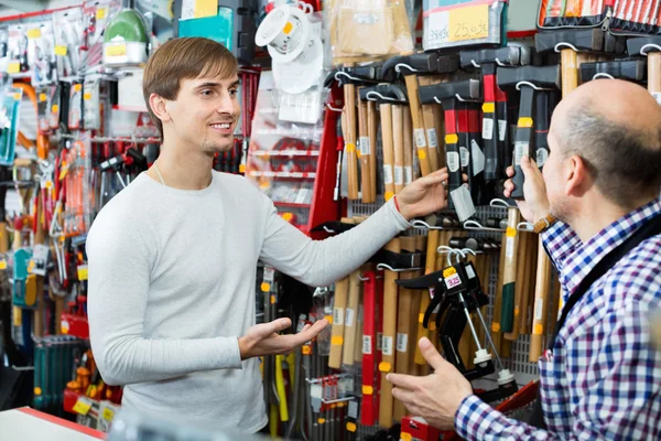 Customer and friendly seller choosing hammer