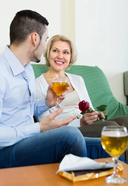 Adult son and senior mother with wine