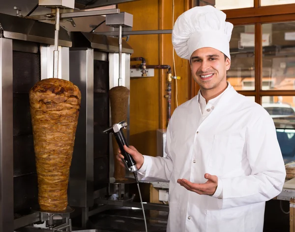 Cook posing near meat for kebab