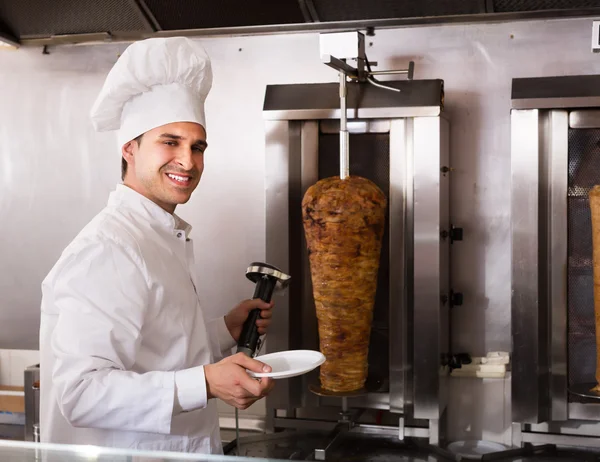 Cook posing near meat for kebab