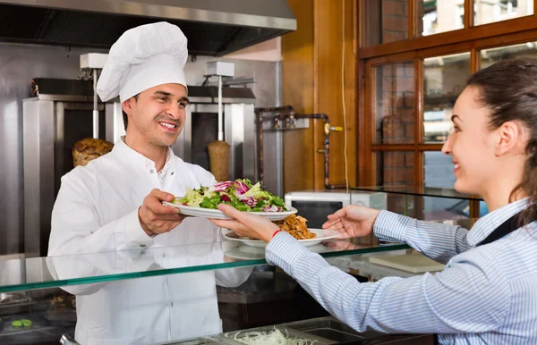 Chef and young waitress taking kebab