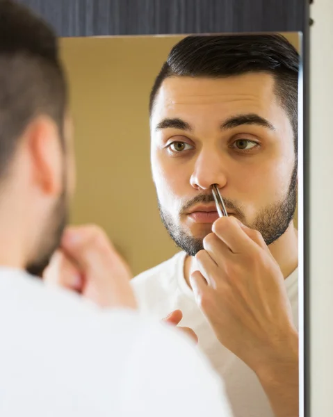 Man removing nose hair