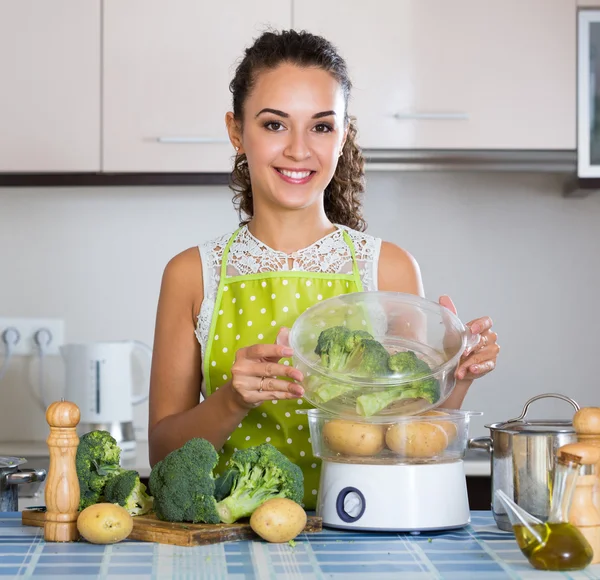 Portrait of cheerful girl steaming vegetables