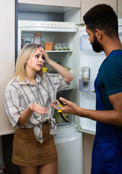 Housewife and handyman near fridge