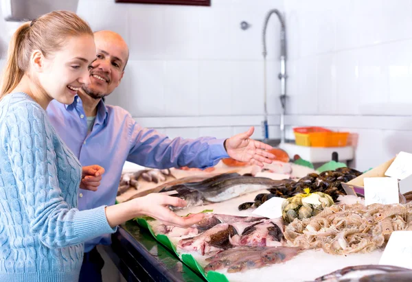 Man and girl choosing cooled seafood in fish