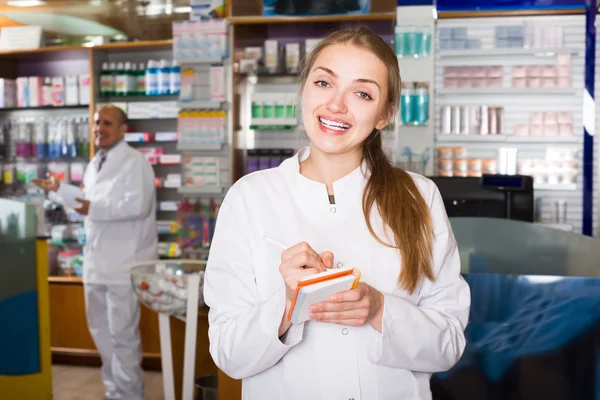 Positive pharmacist standing at pay desk