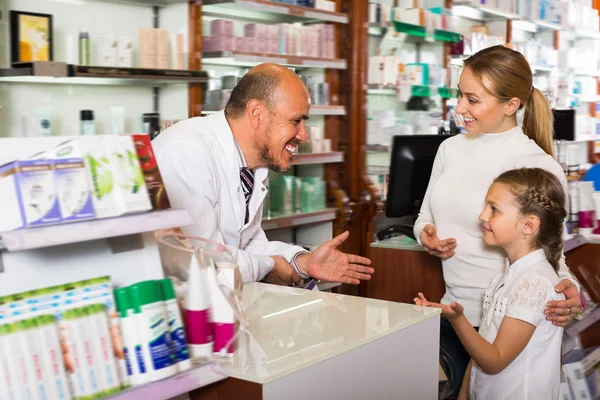 Happy mature male pharmacist helping customers
