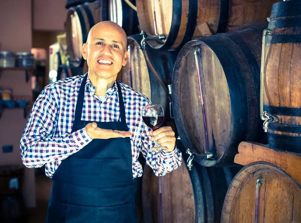 Seller pouring wine from wood barrel