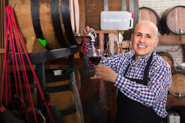 Wine maker taking wine from wood