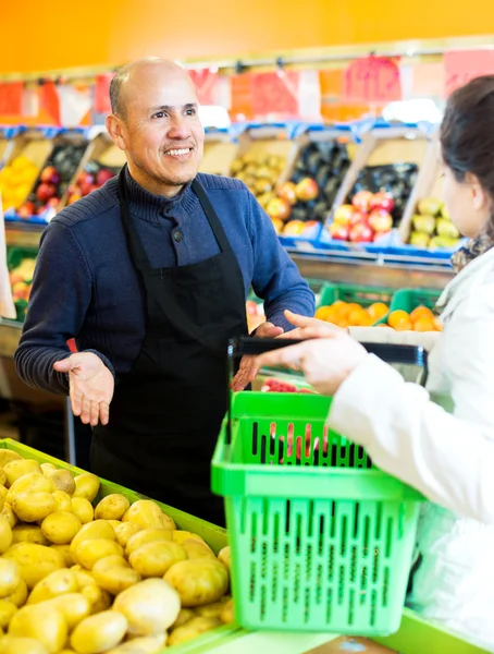 Friendly worker selling vegetables to female customer