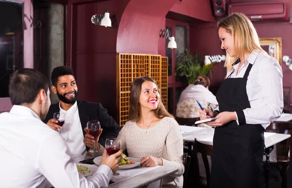 Smiling waitress and guests at the table