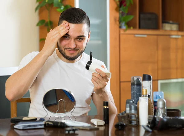 Man applying facial cream at home