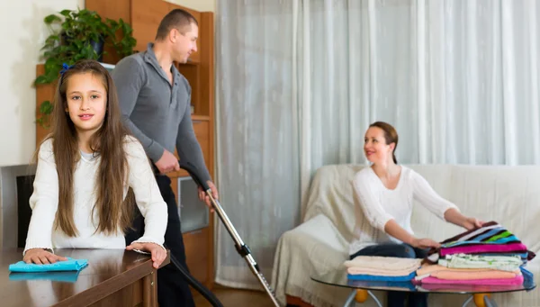 Family of three tidying up a room