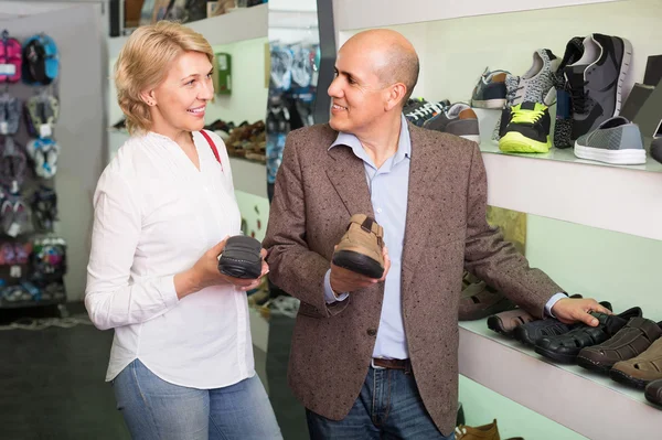 Two retirees together choosing pair of shoes